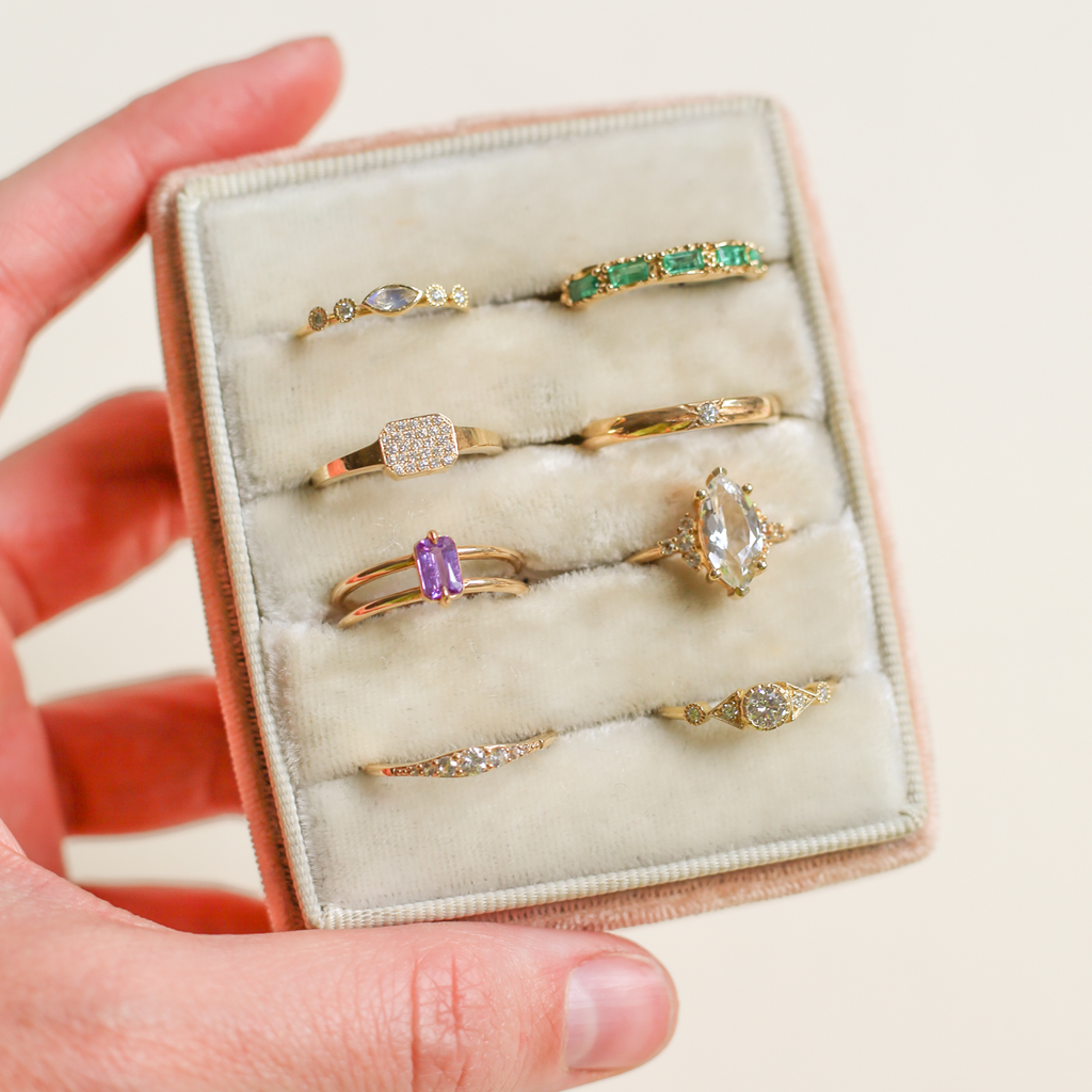 Assorted rings with diamonds and gemstones in a traveling jewelry box.